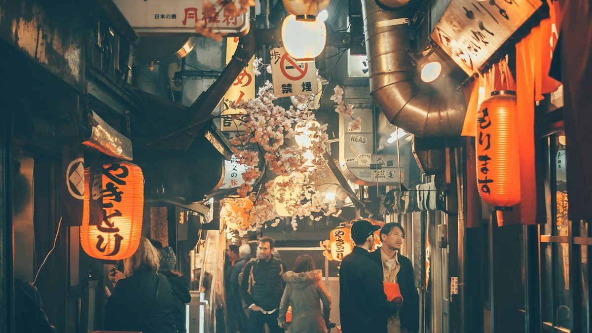 A narrow street in Tokyo at night, lit by paper lanterns